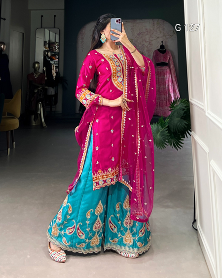Woman wearing a traditional outfit with a pink dupatta and blue lehenga in a room.