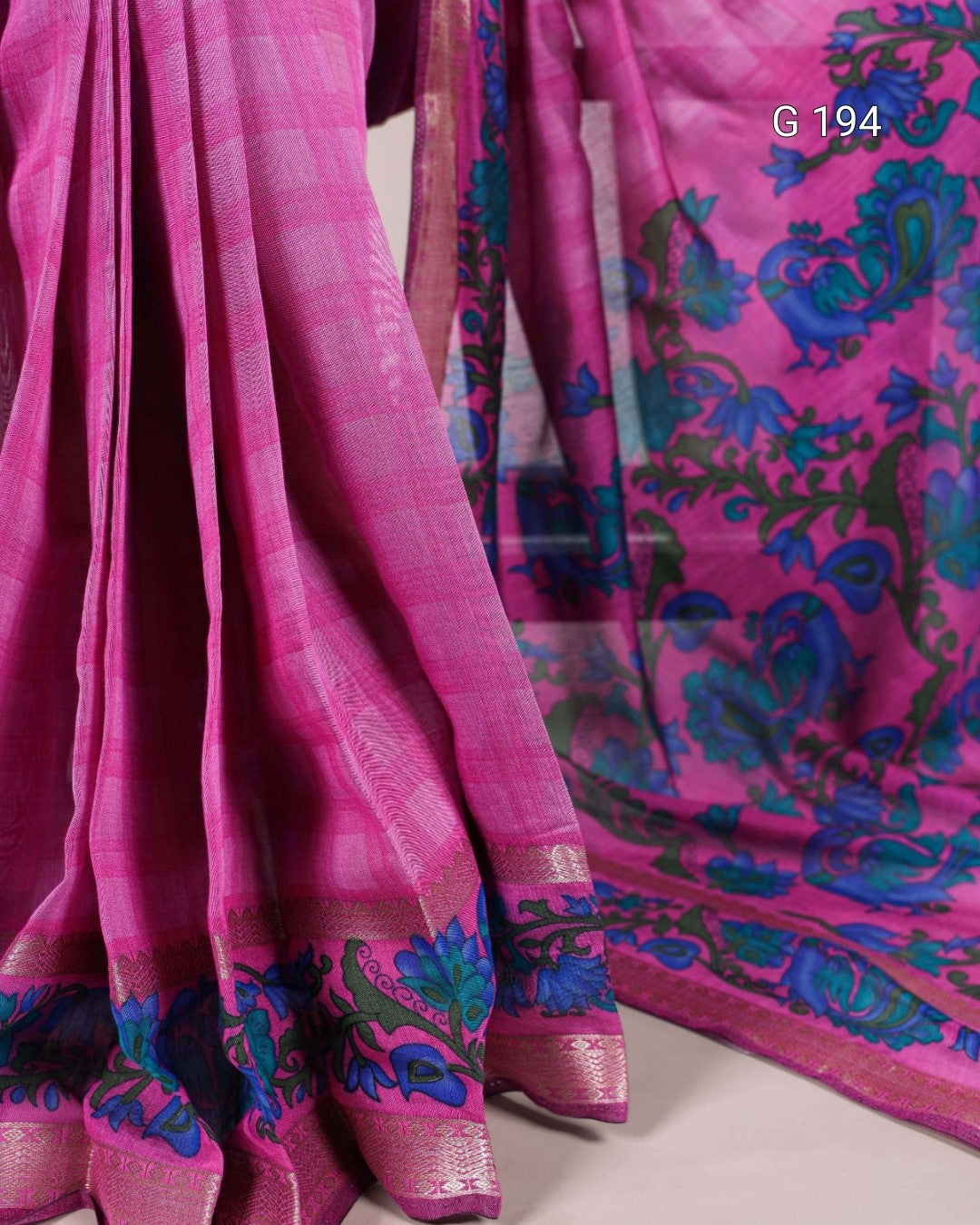 Pink saree with blue and green floral patterns on a white background