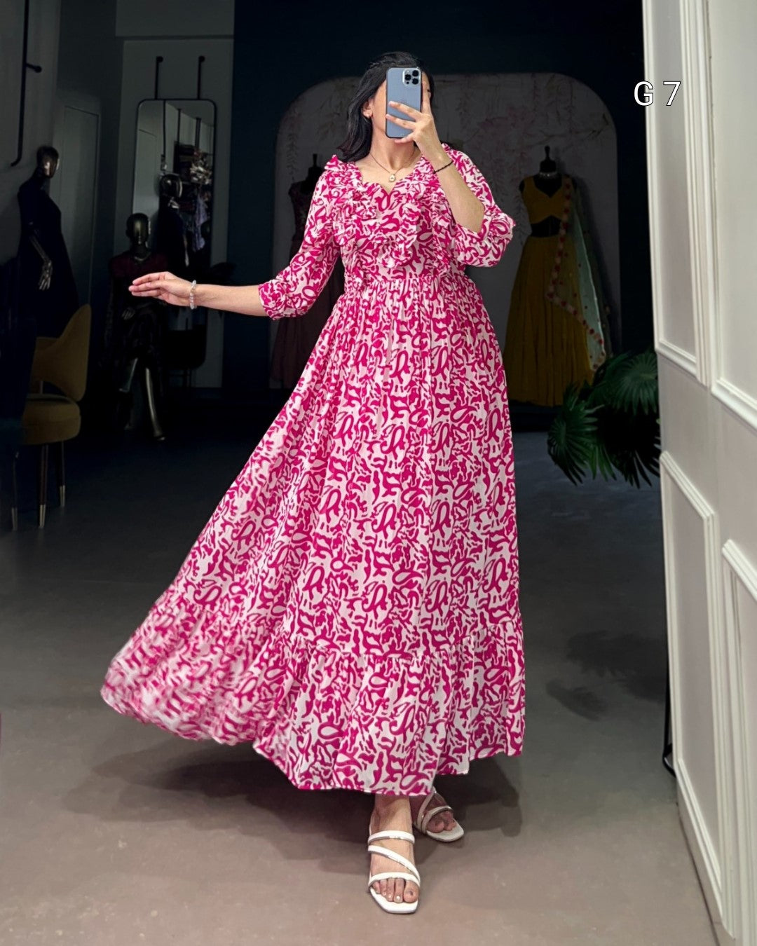 Person wearing a pink floral dress in a room with mirrors and clothing.
