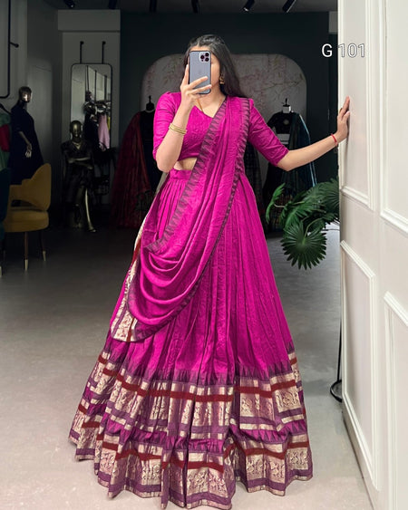 Person wearing a vibrant pink saree with a matching blouse in a room.