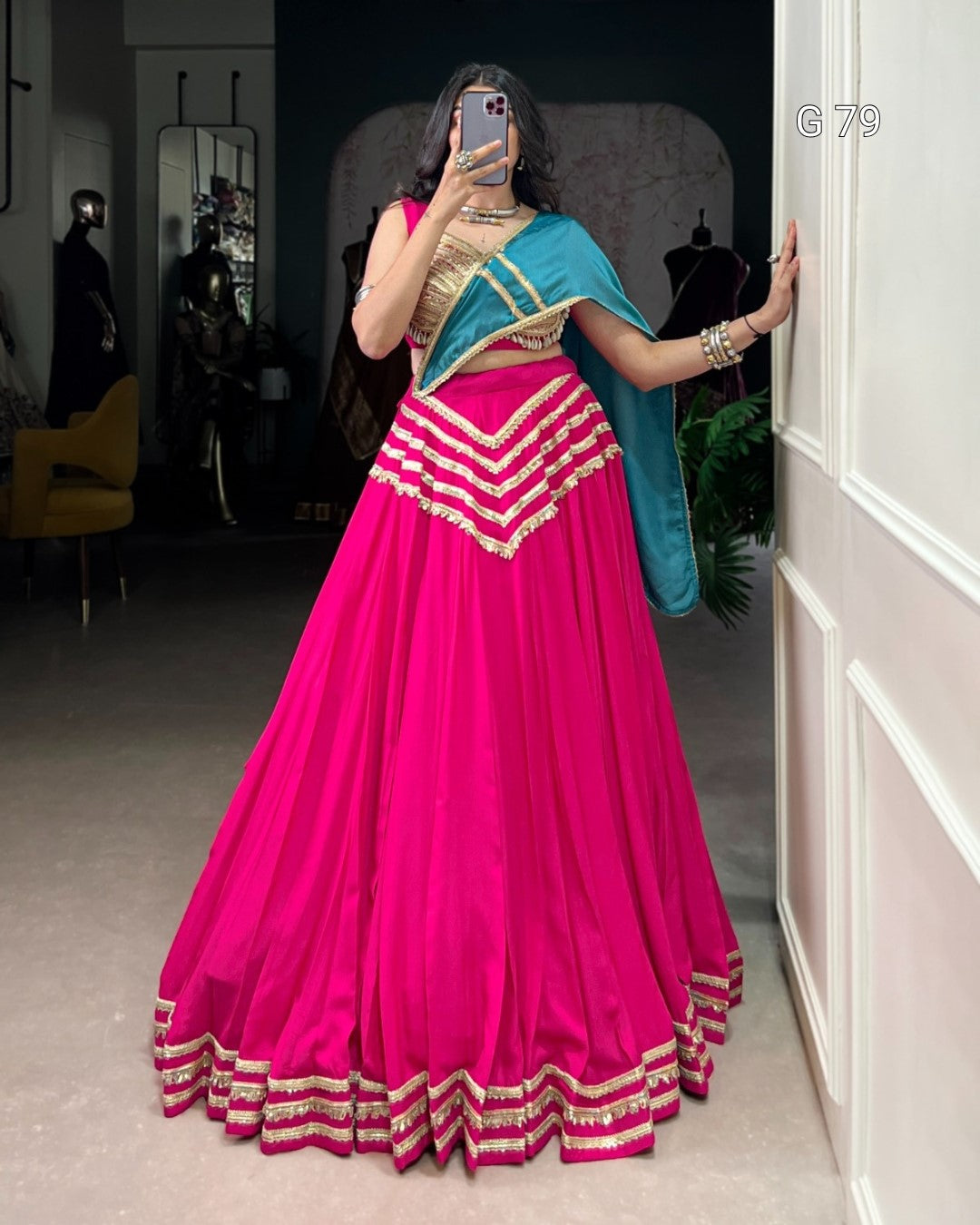 Person wearing a bright pink traditional outfit with gold accents in a room.