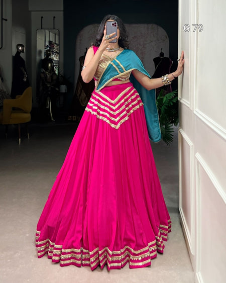 Person wearing a bright pink traditional outfit with gold accents in a room.