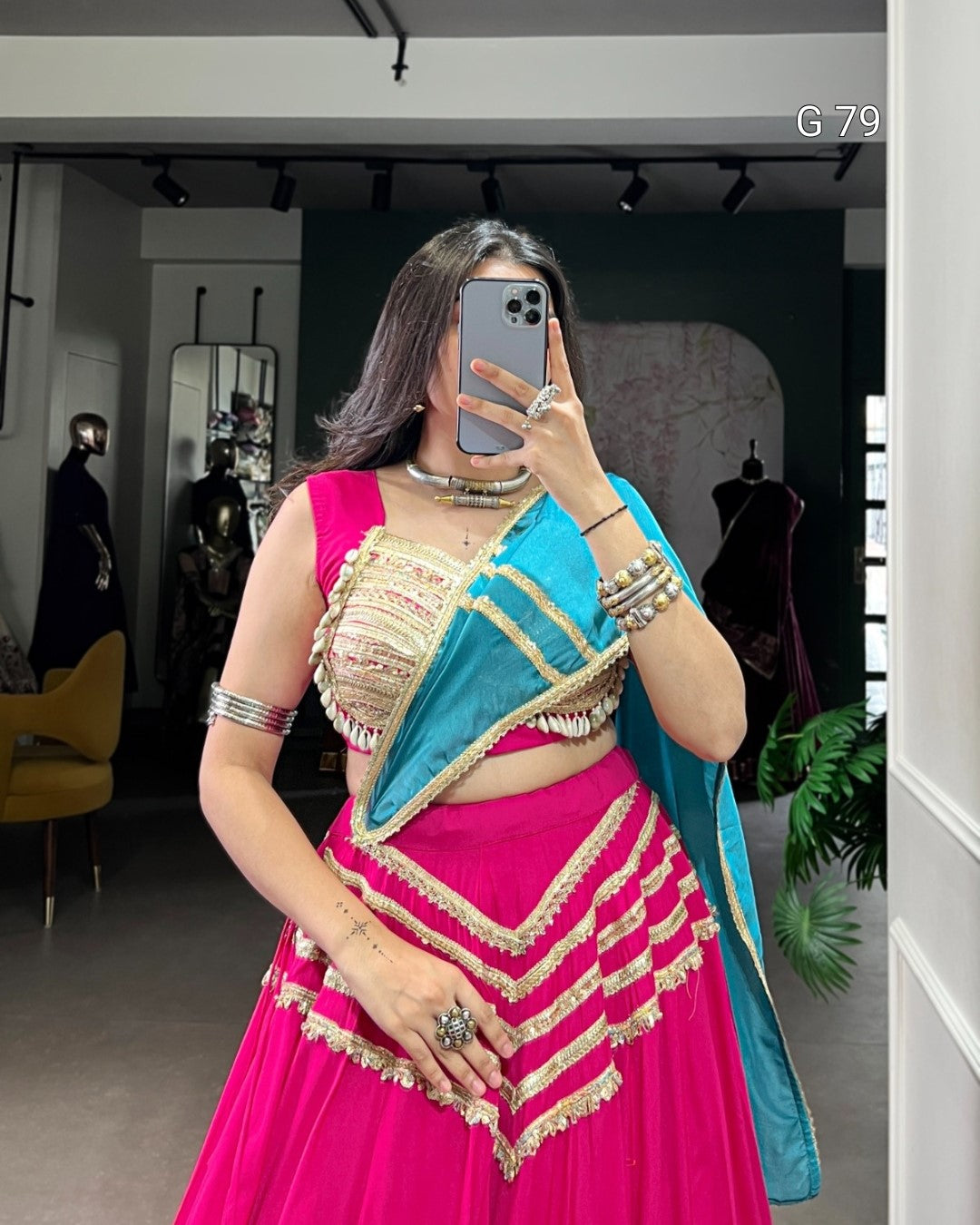 Woman taking a mirror selfie wearing a traditional outfit with a pink and blue saree.