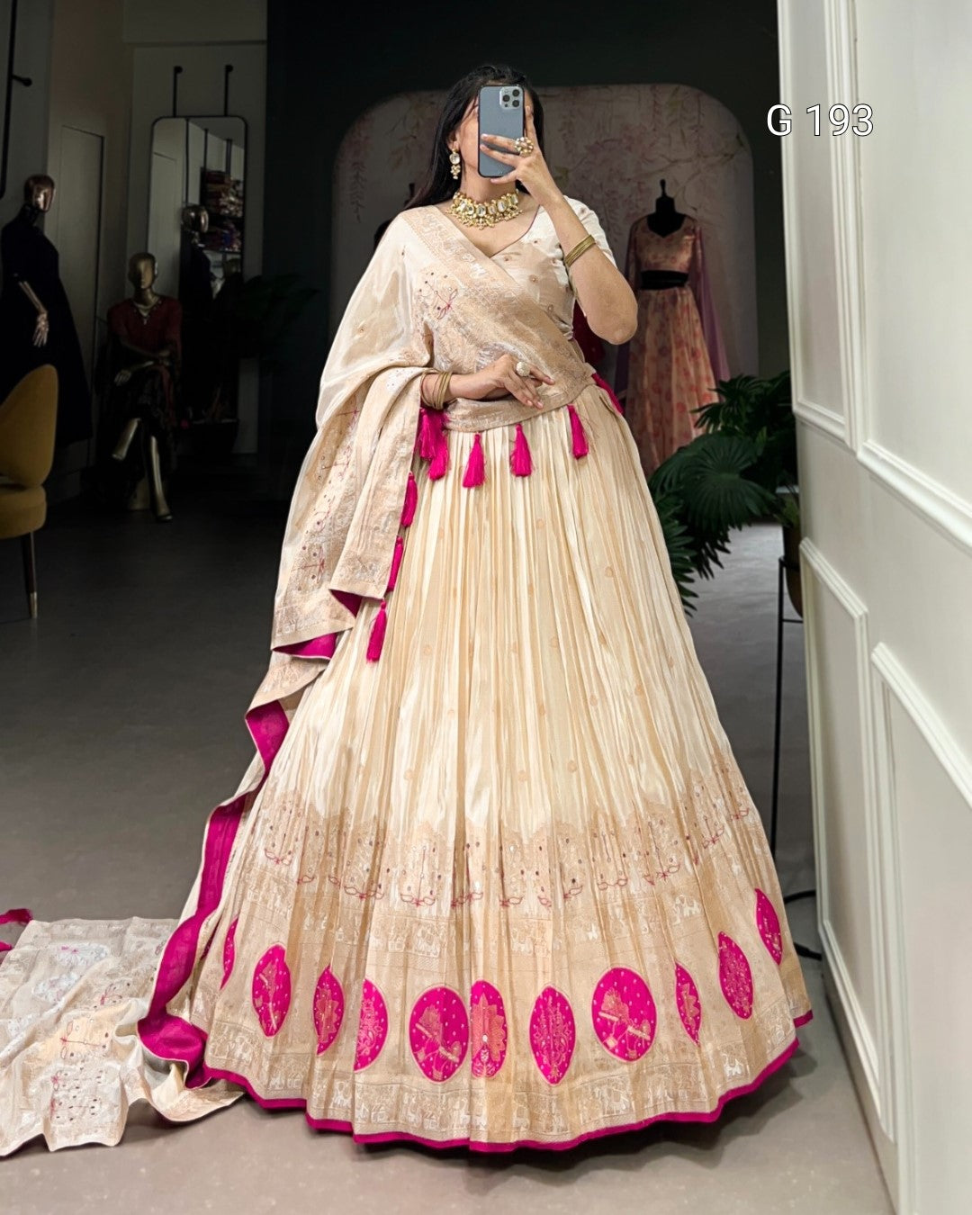 Woman wearing a traditional outfit with pink and beige design in a room.