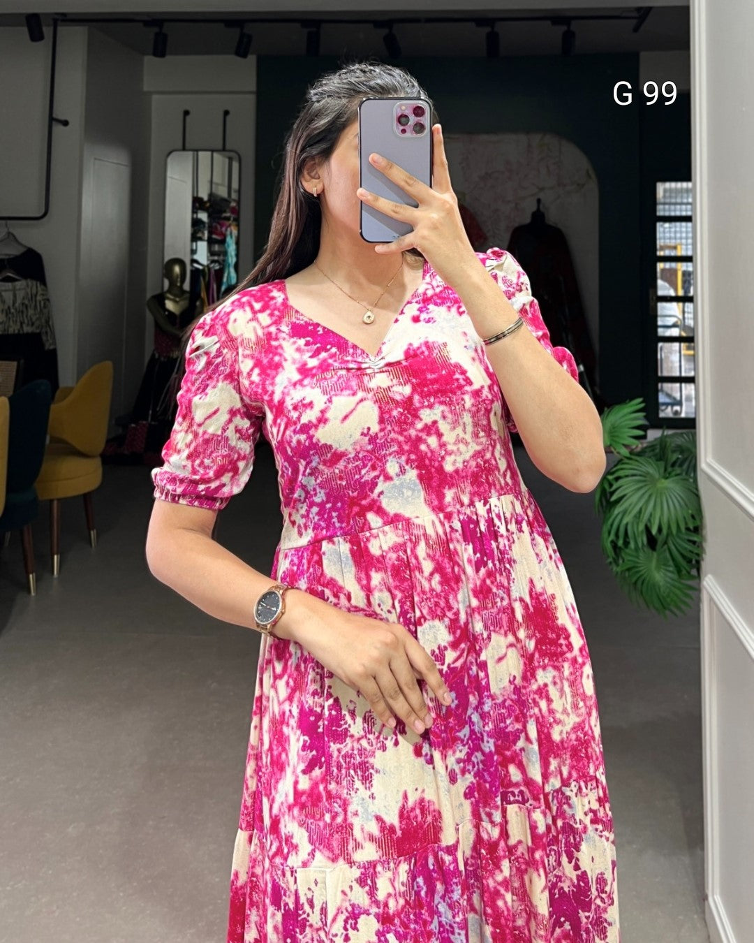 Woman taking a mirror selfie wearing a pink and white patterned dress.