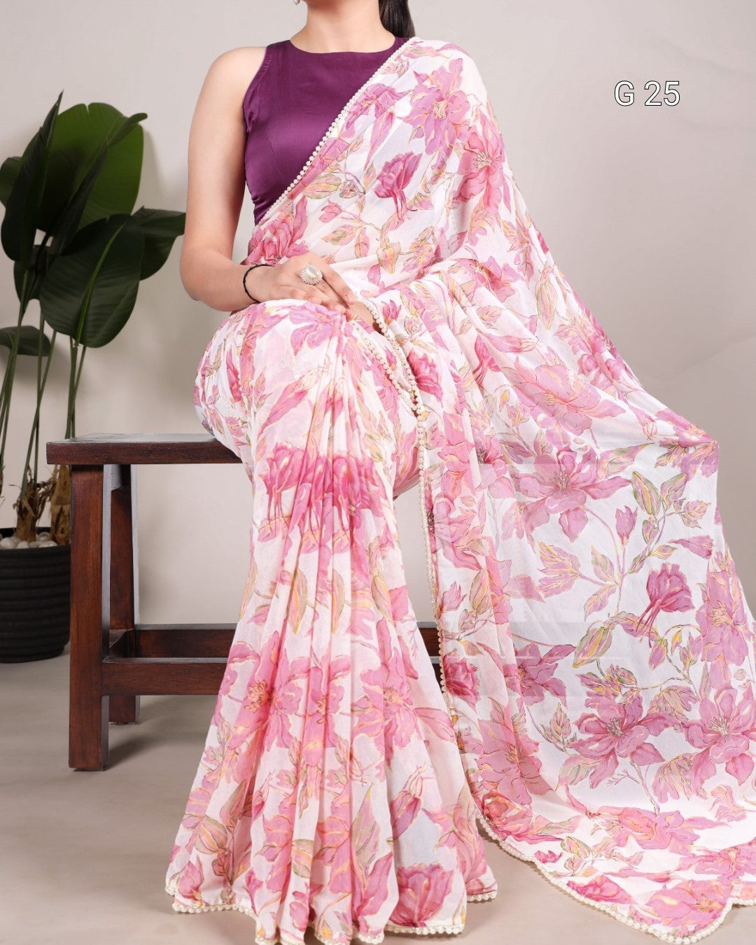 Woman wearing a pink floral saree with a plain background