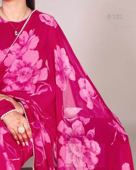 Person wearing a bright pink saree with floral patterns on a plain background