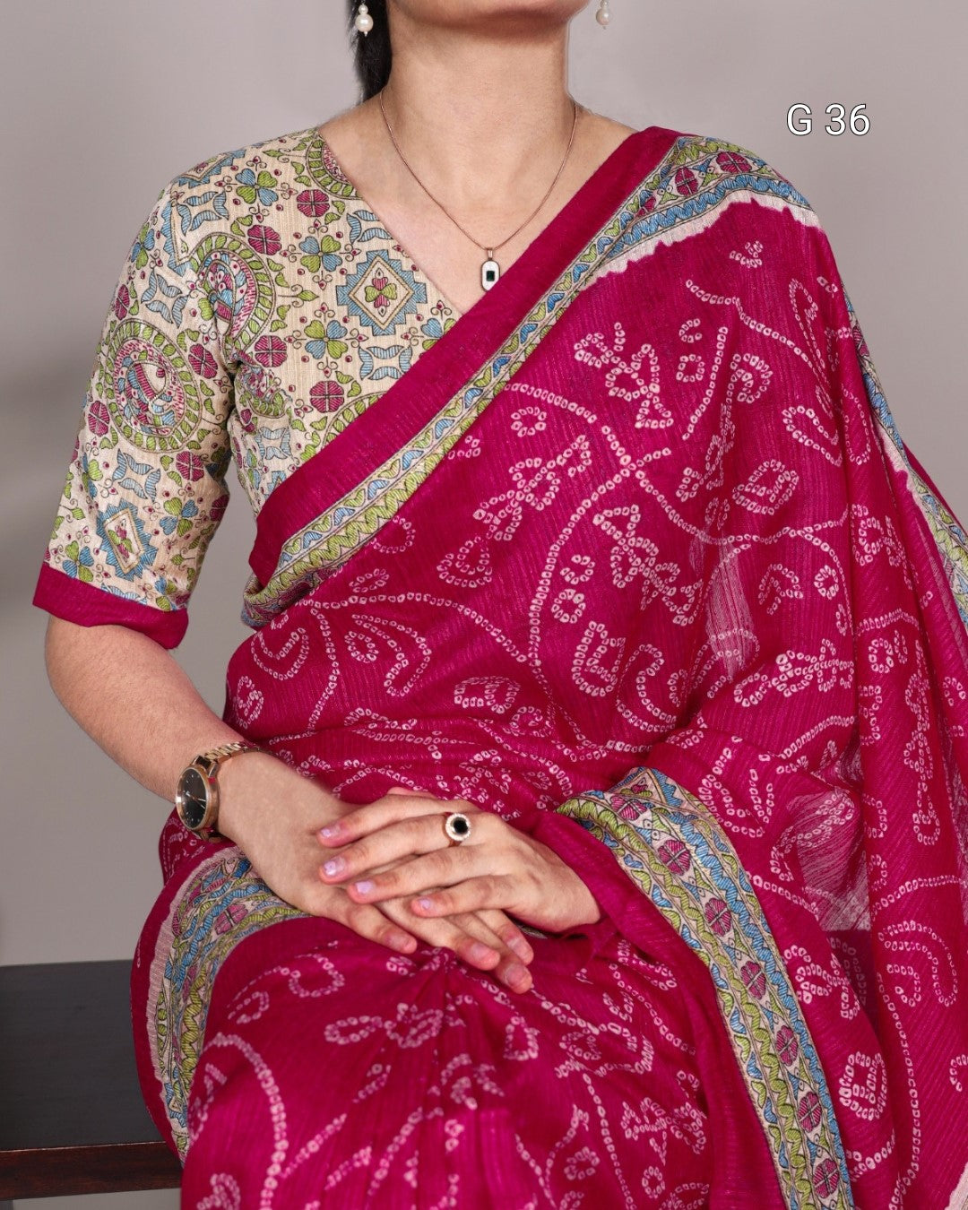 Woman wearing a pink saree with intricate patterns against a neutral background