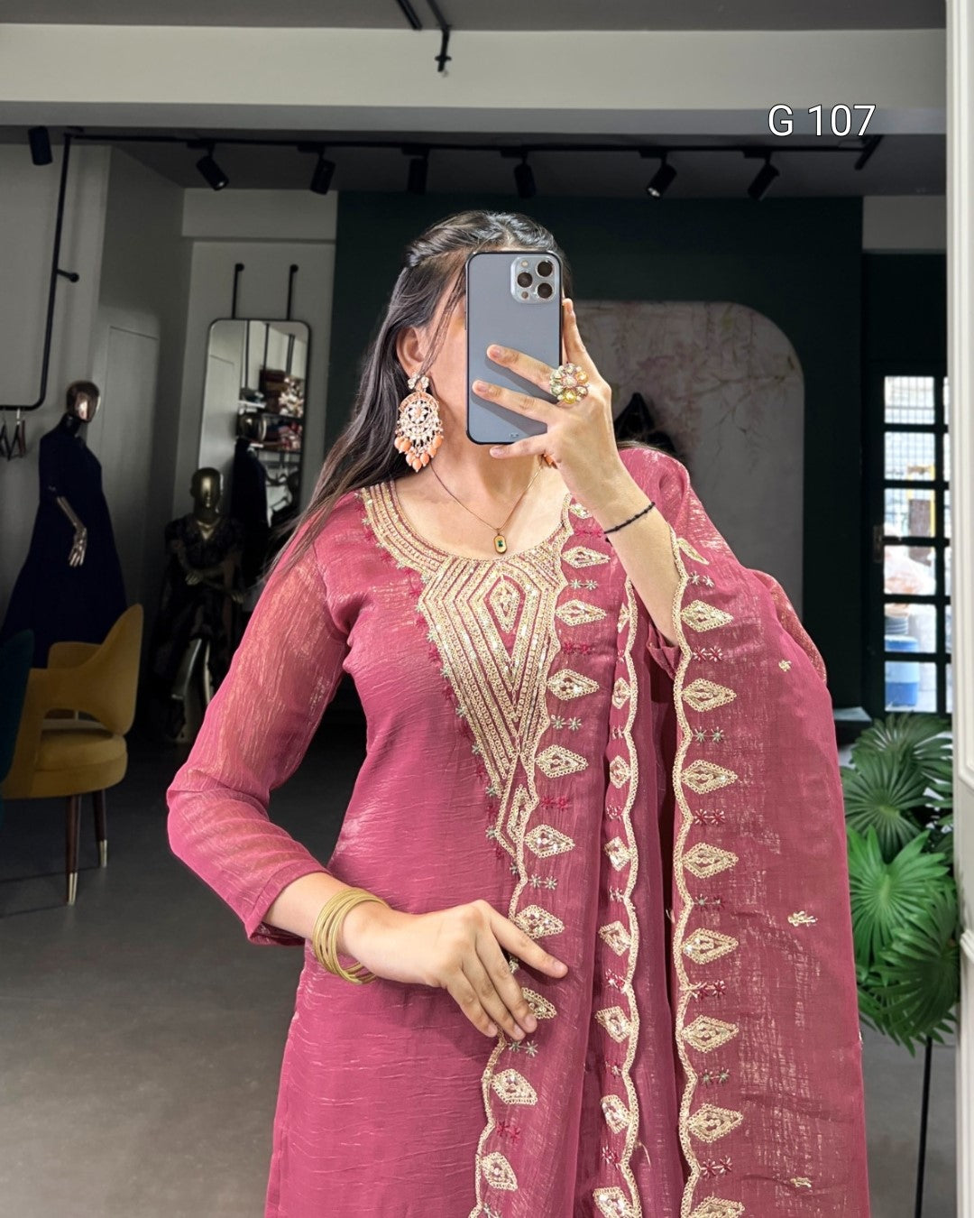 Person wearing a pink traditional outfit with gold embroidery in a modern indoor setting.