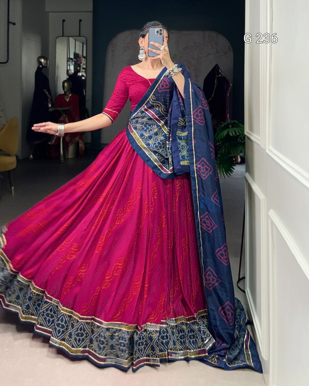 Woman wearing a pink and blue traditional outfit with a saree in a room.