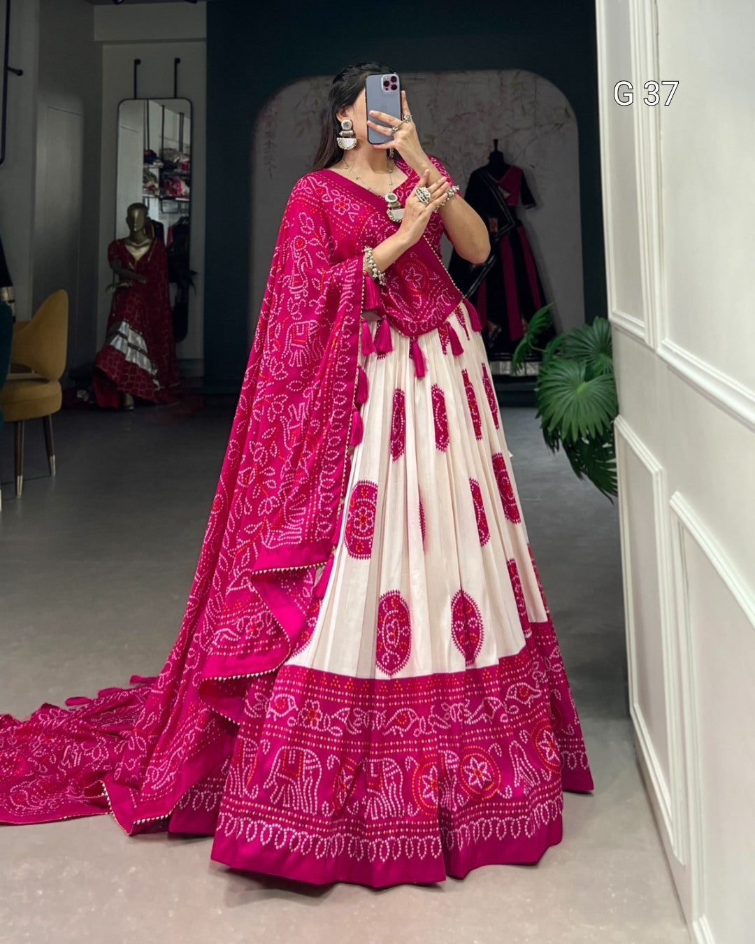 Woman wearing a pink and white traditional outfit with a matching dupatta in a room.