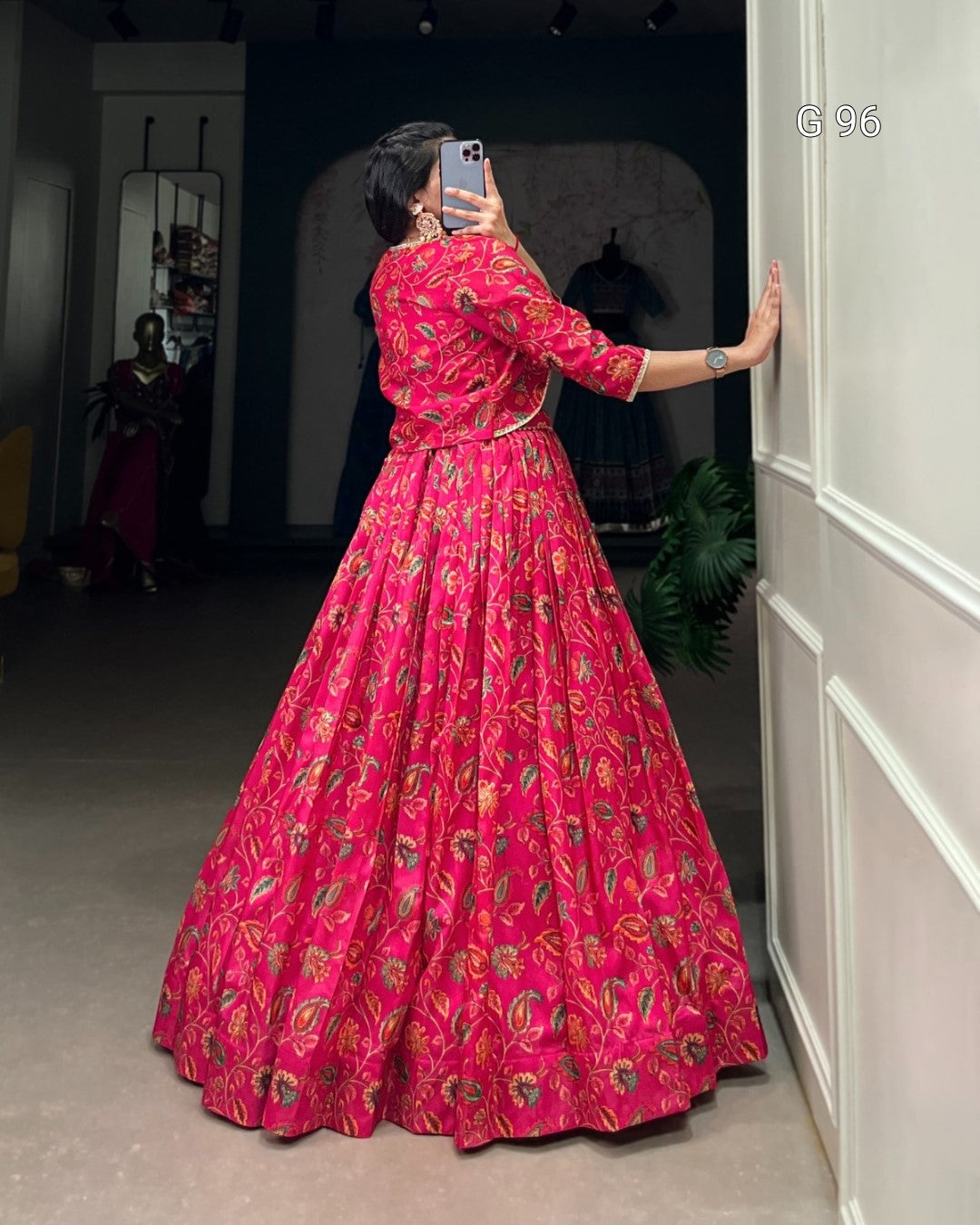 Person wearing a vibrant red patterned dress taking a mirror selfie.