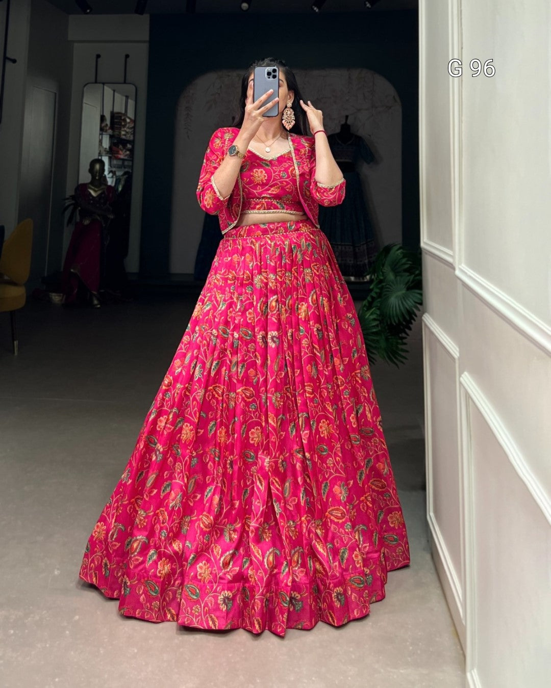 Person wearing a vibrant pink traditional outfit with floral patterns in a room.