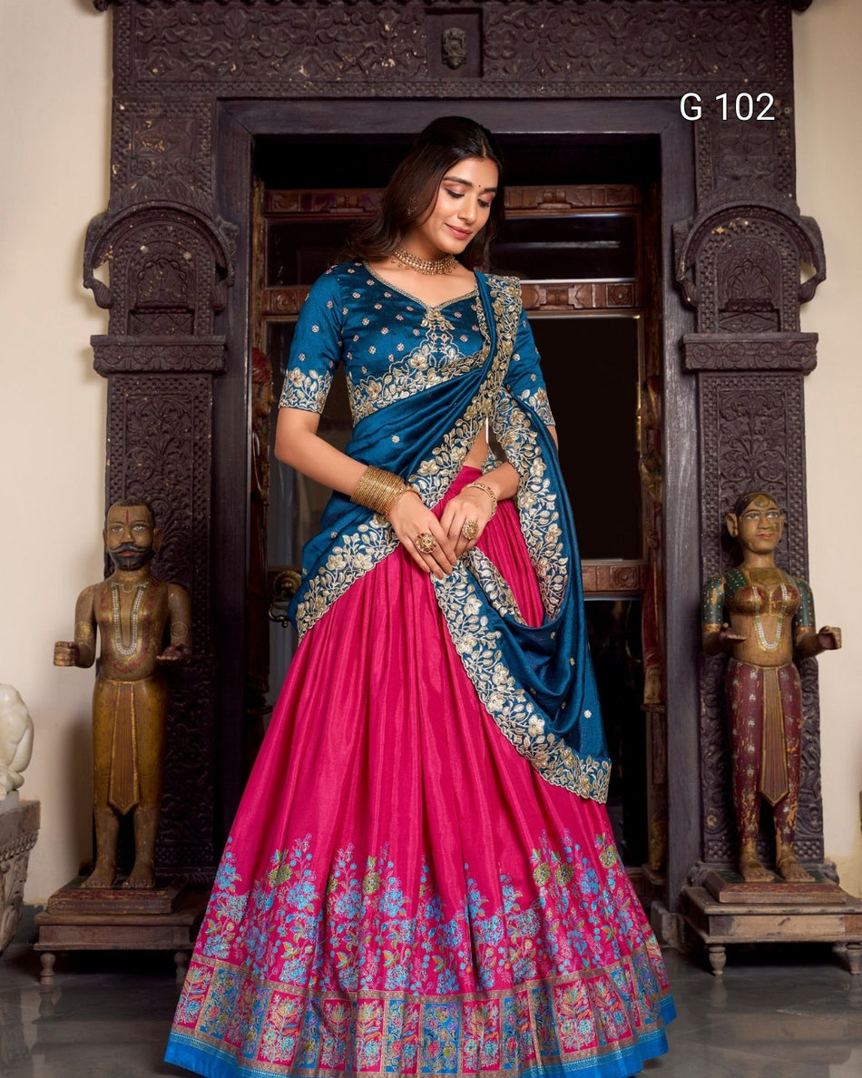 Woman in a blue and pink saree standing in front of a decorative entrance.