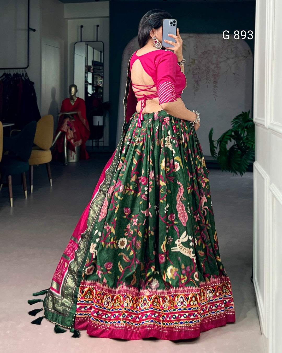 Person wearing a traditional green and pink outfit with floral patterns in a room.