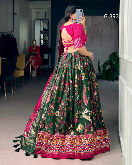 Person wearing a traditional green and pink outfit with floral patterns in a room.
