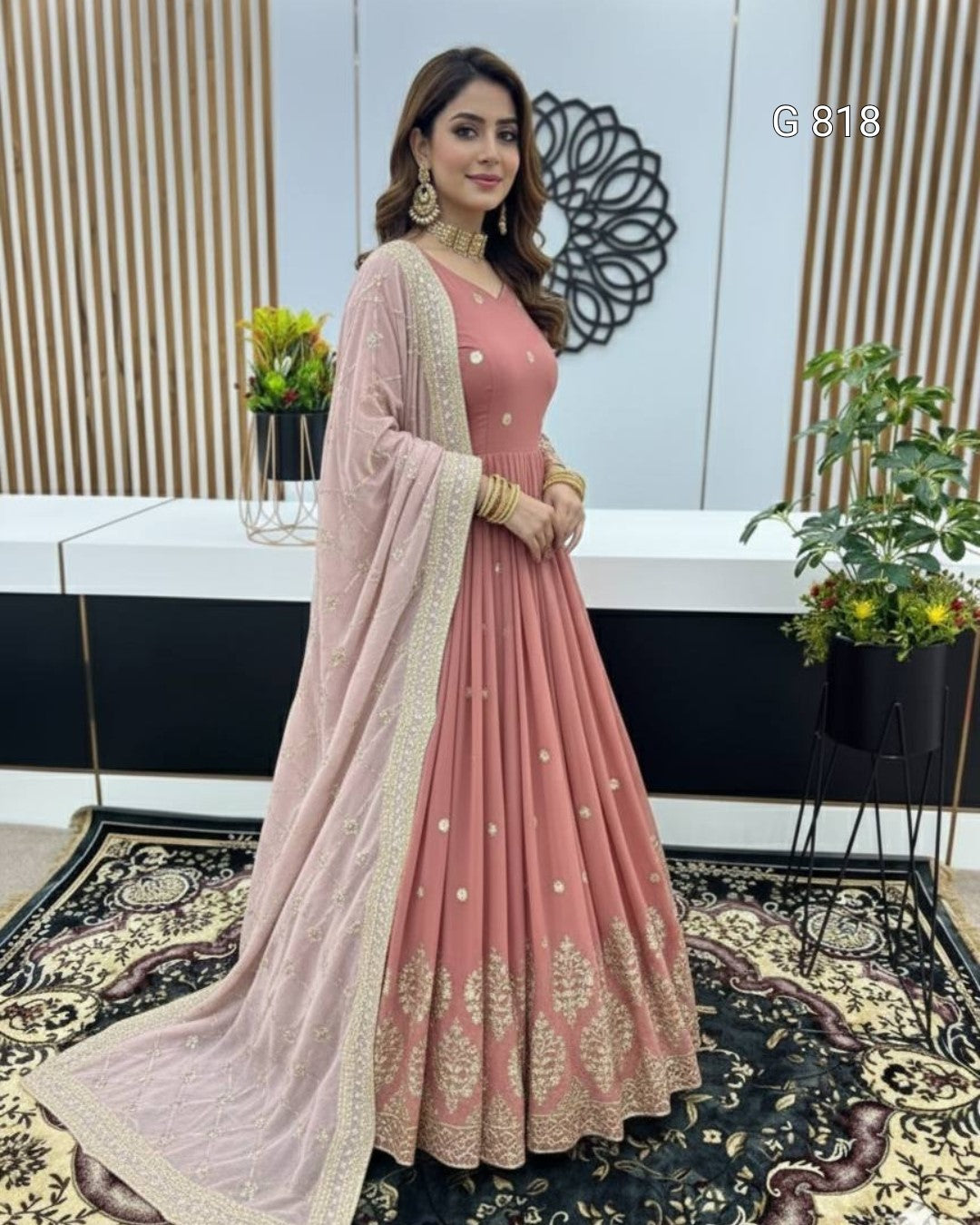 Woman in a pink traditional outfit with a sheer dupatta in an indoor setting.