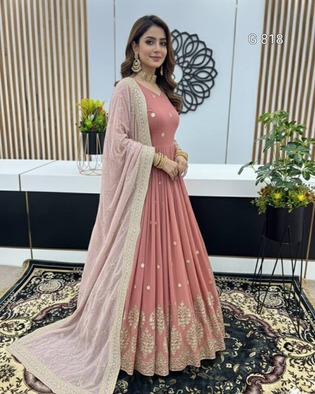 Woman in a pink traditional outfit with a sheer dupatta in an indoor setting.