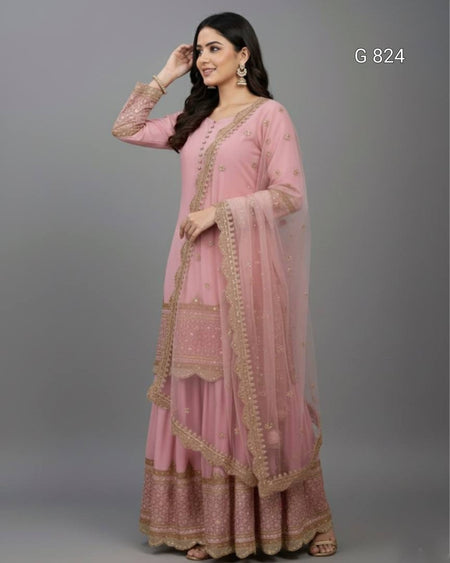 Woman wearing a pink traditional outfit with gold embroidery on a gray background