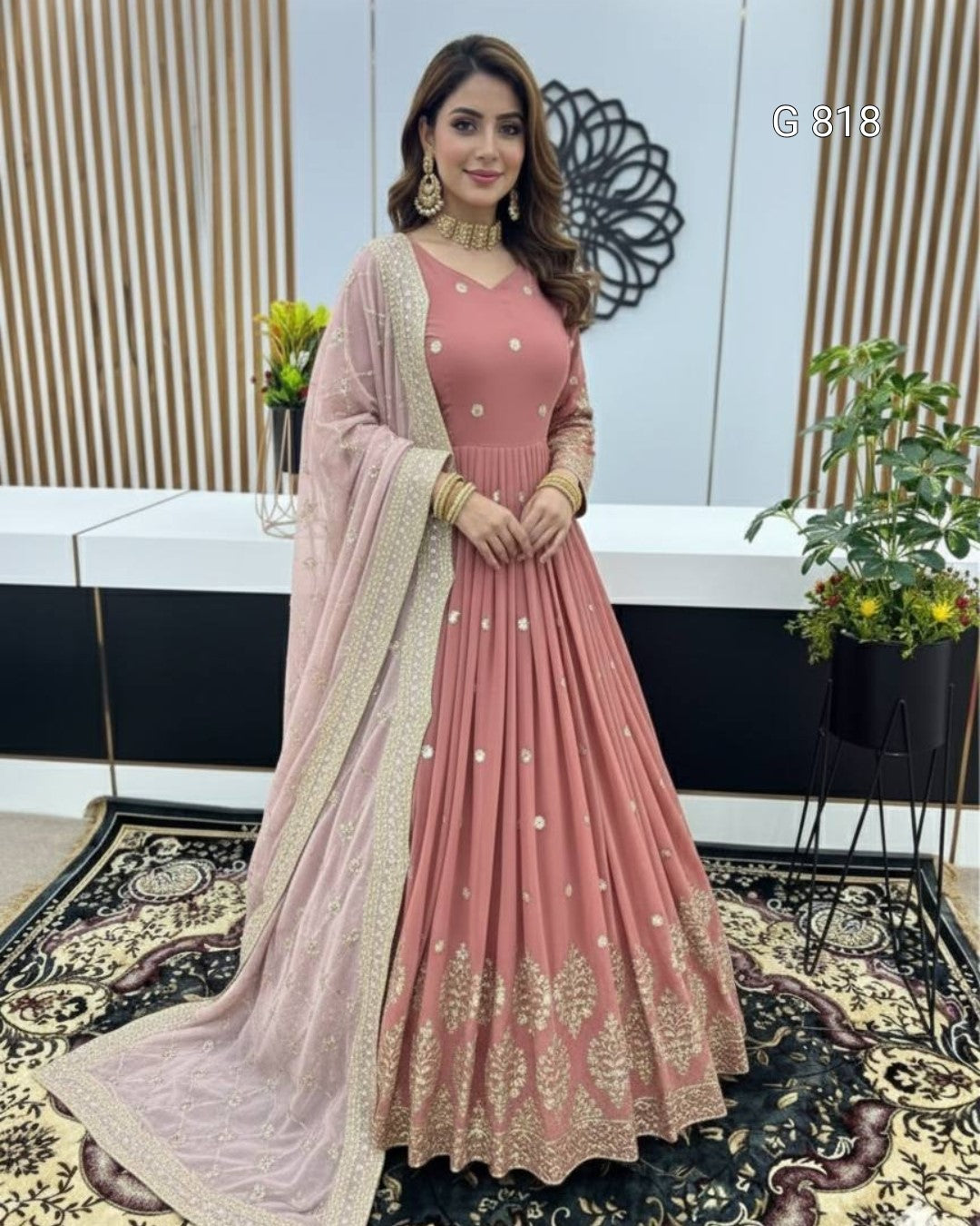 Woman in a pink traditional outfit with gold details in an indoor setting.