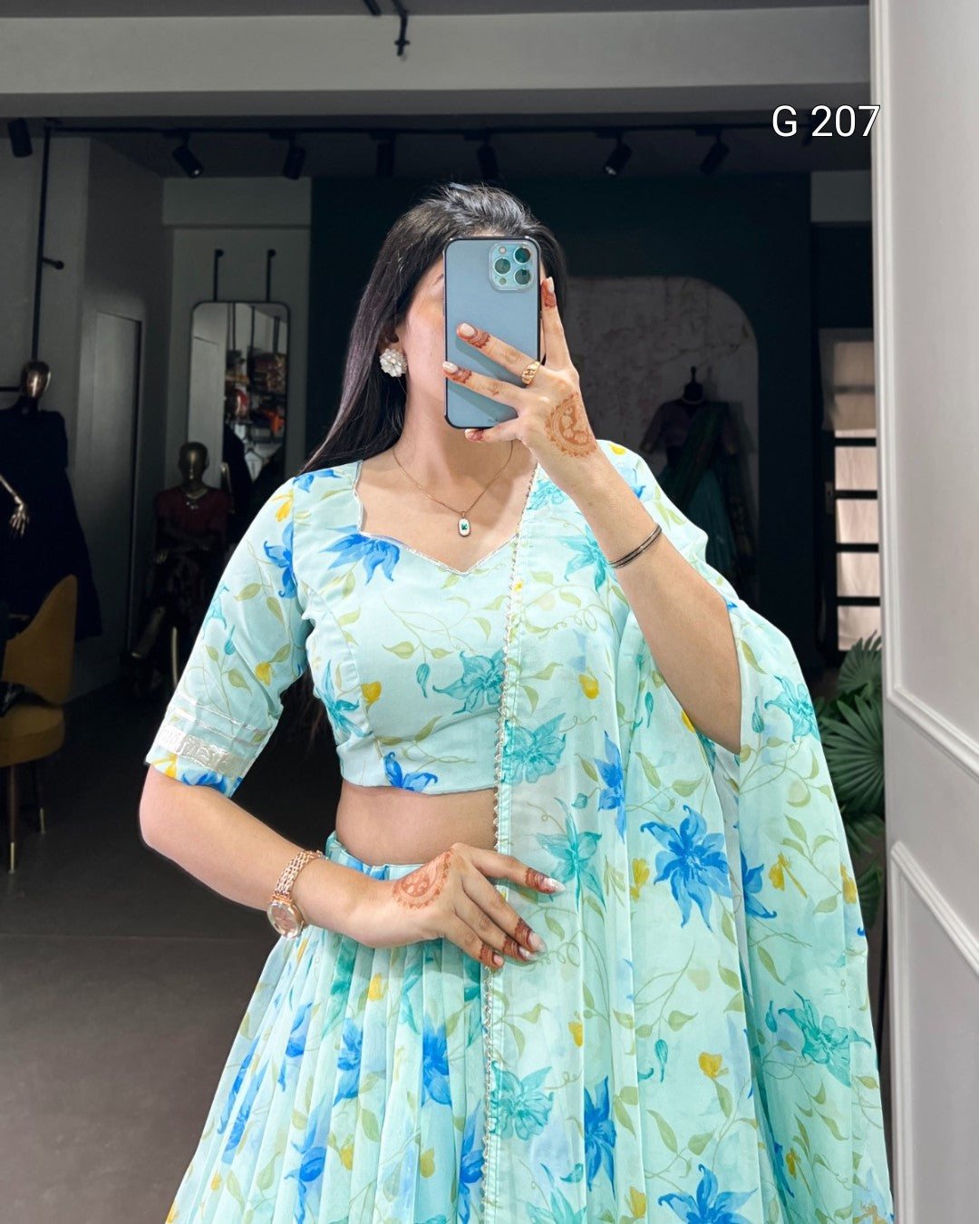 Person wearing a light blue floral outfit taking a mirror selfie.