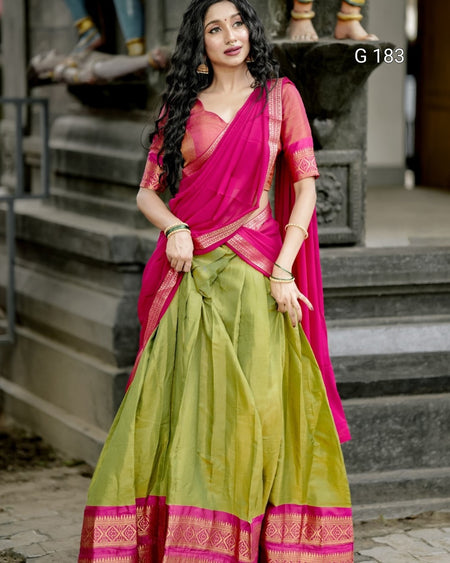 Woman wearing a pink and green saree standing on steps.