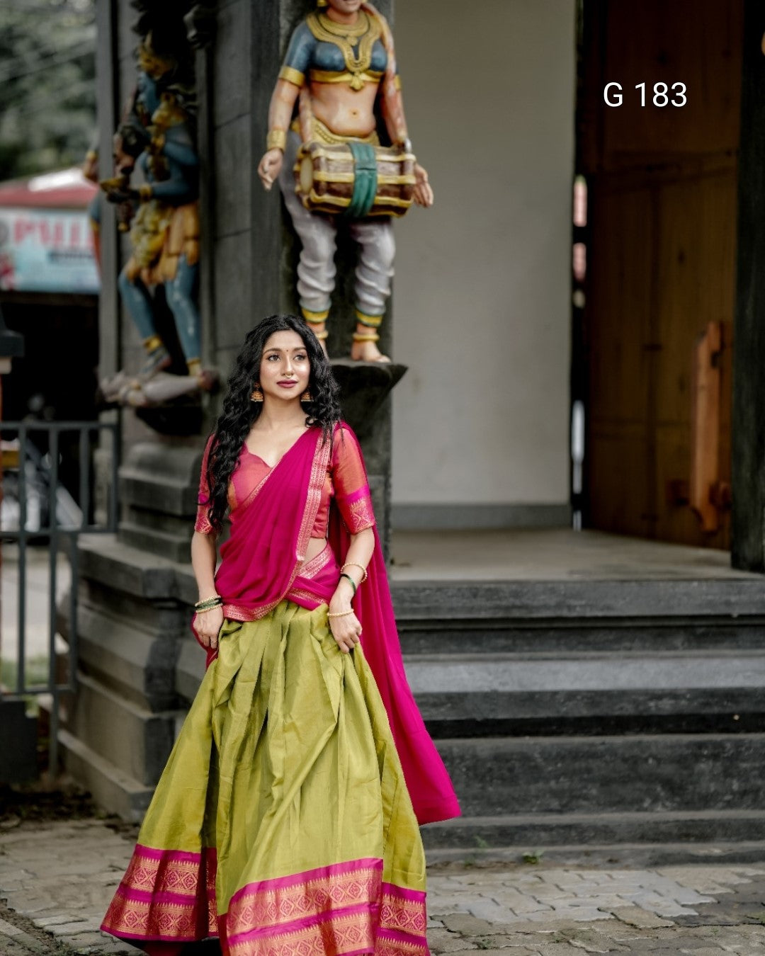 Woman in a traditional outfit standing in front of a statue
