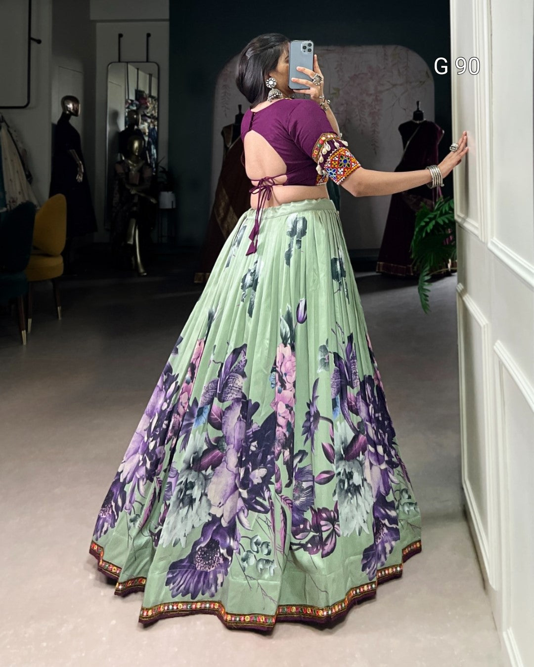 Woman taking a mirror selfie wearing a floral lehenga and purple blouse.