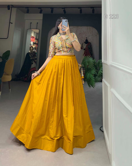 Person wearing a colorful top and yellow skirt in a room with plants and furniture.