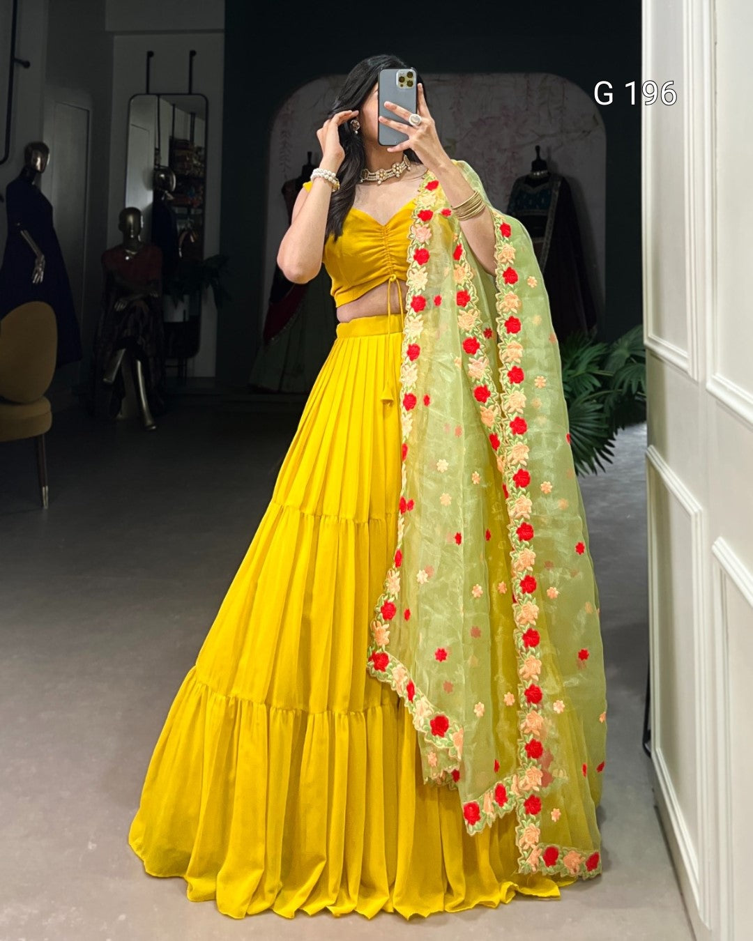 Person wearing a yellow traditional outfit with a floral dupatta in a room setting.