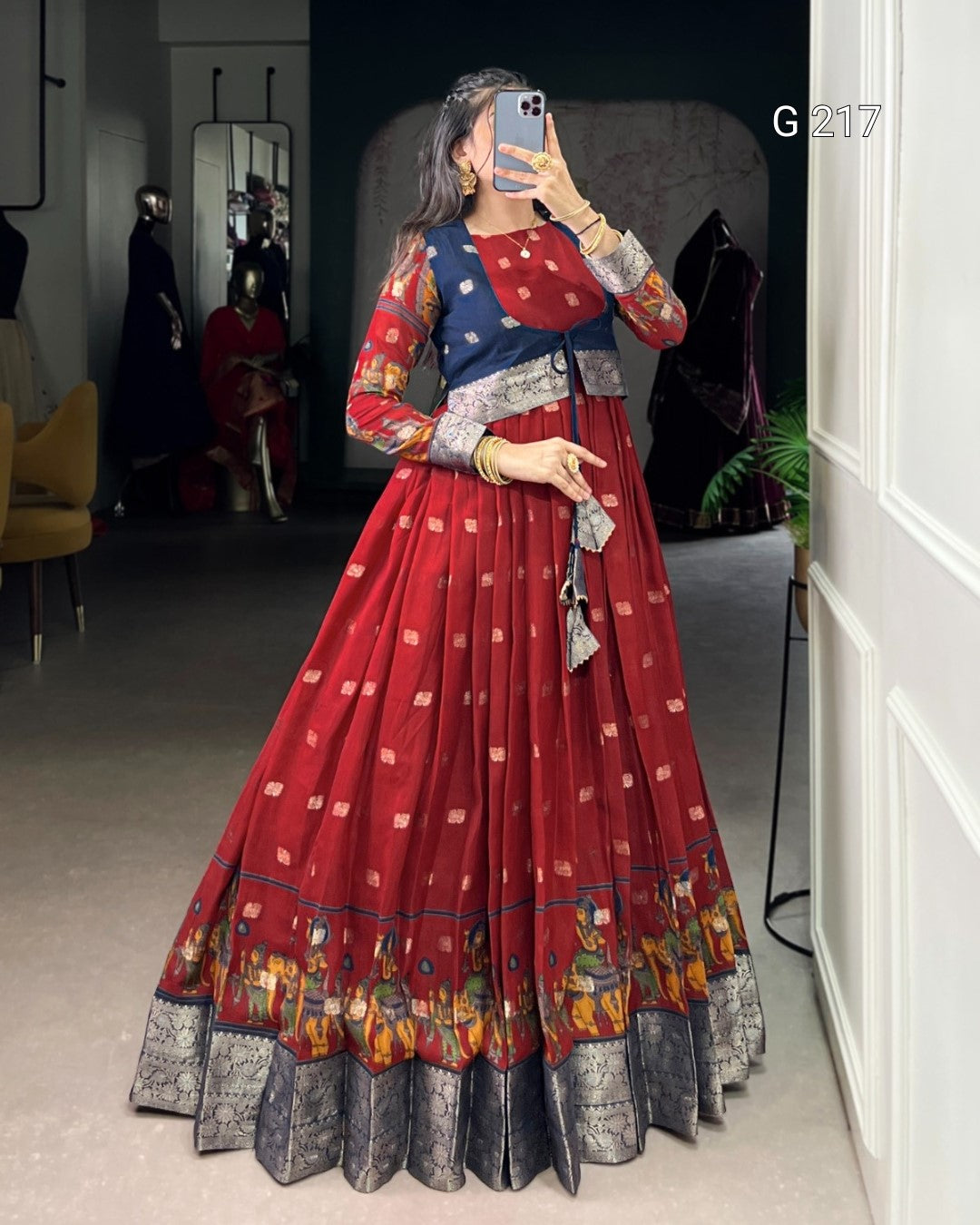 Woman taking a mirror selfie wearing a red and patterned dress in a room.