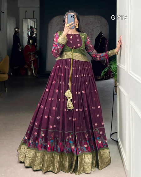 Person wearing a traditional outfit with a long purple dress and green top, standing in a room.