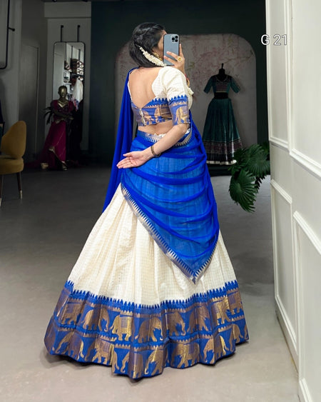Woman wearing a blue and white traditional outfit with elephant patterns, taking a mirror selfie.