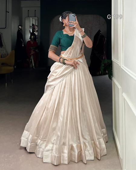 Person wearing a white saree with a green blouse in a room.