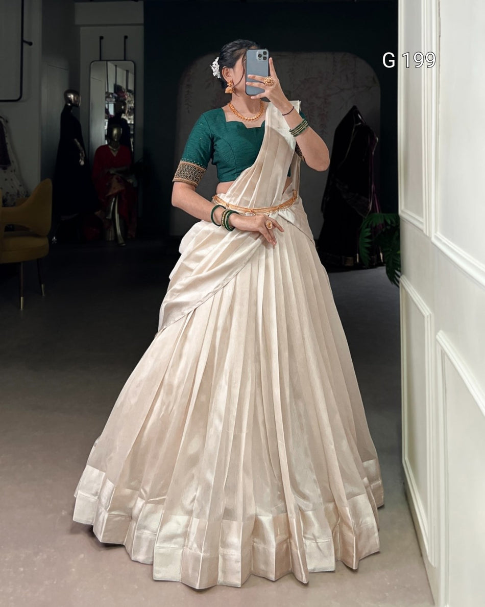 Person wearing a white saree with a green blouse in a room.
