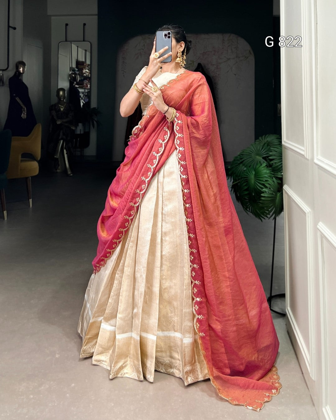 Person wearing a traditional saree with red and gold colors in an indoor setting.