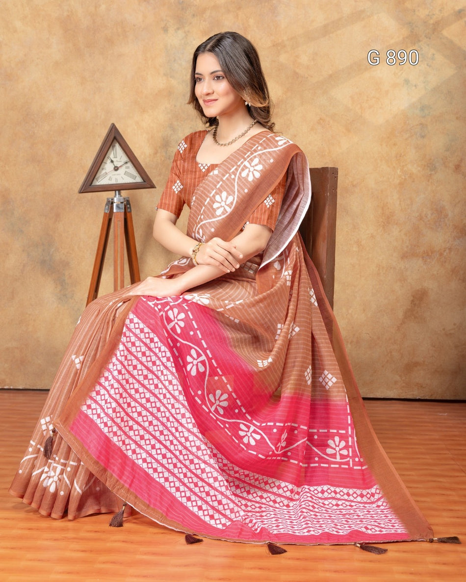 Woman wearing a traditional saree with a brown and red pattern, sitting on a chair against a beige wall.