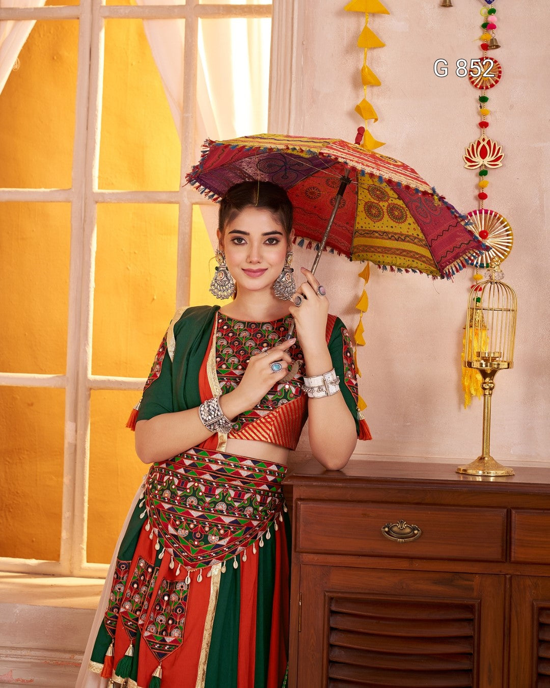 Woman in traditional outfit holding a colorful umbrella indoors
