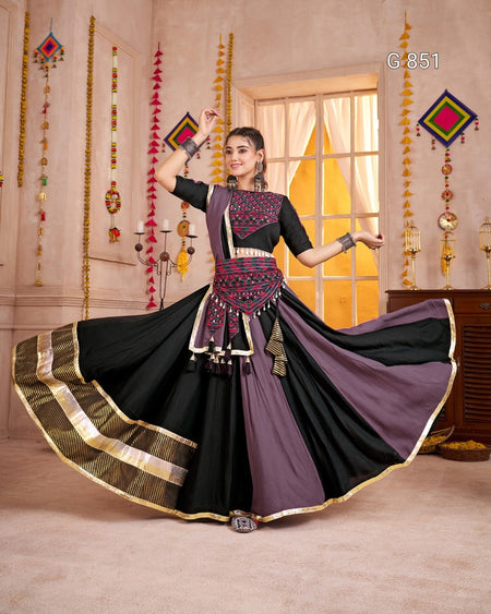Woman in a black and purple traditional outfit with a flowing skirt in a decorated room.