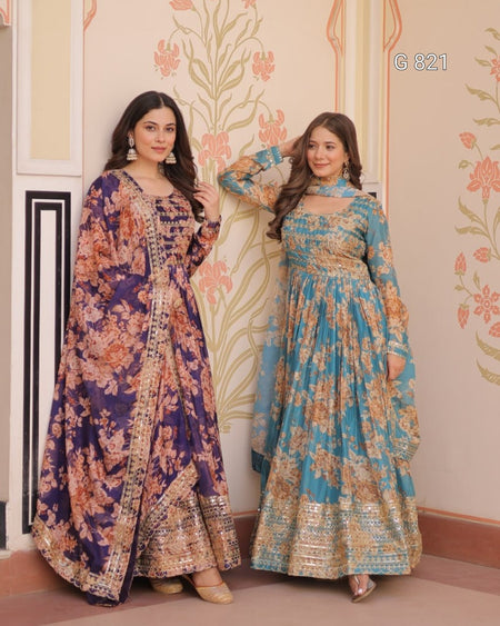 Two women in floral outfits standing against a decorative wall.