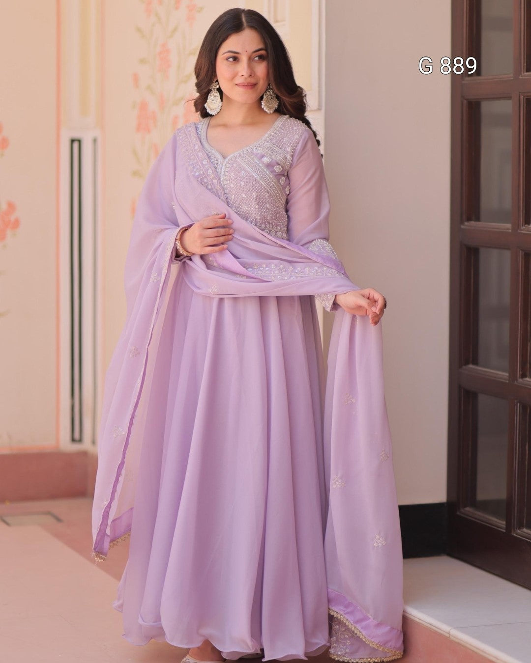 Woman wearing a lavender traditional outfit with a matching dupatta indoors.