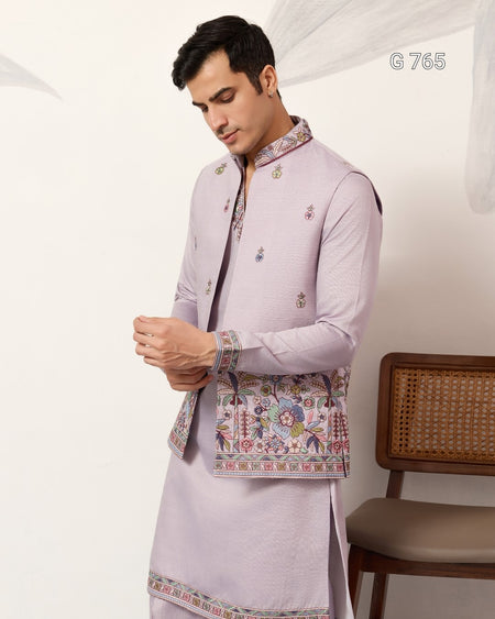 Man wearing a light purple traditional outfit with intricate patterns on a white background