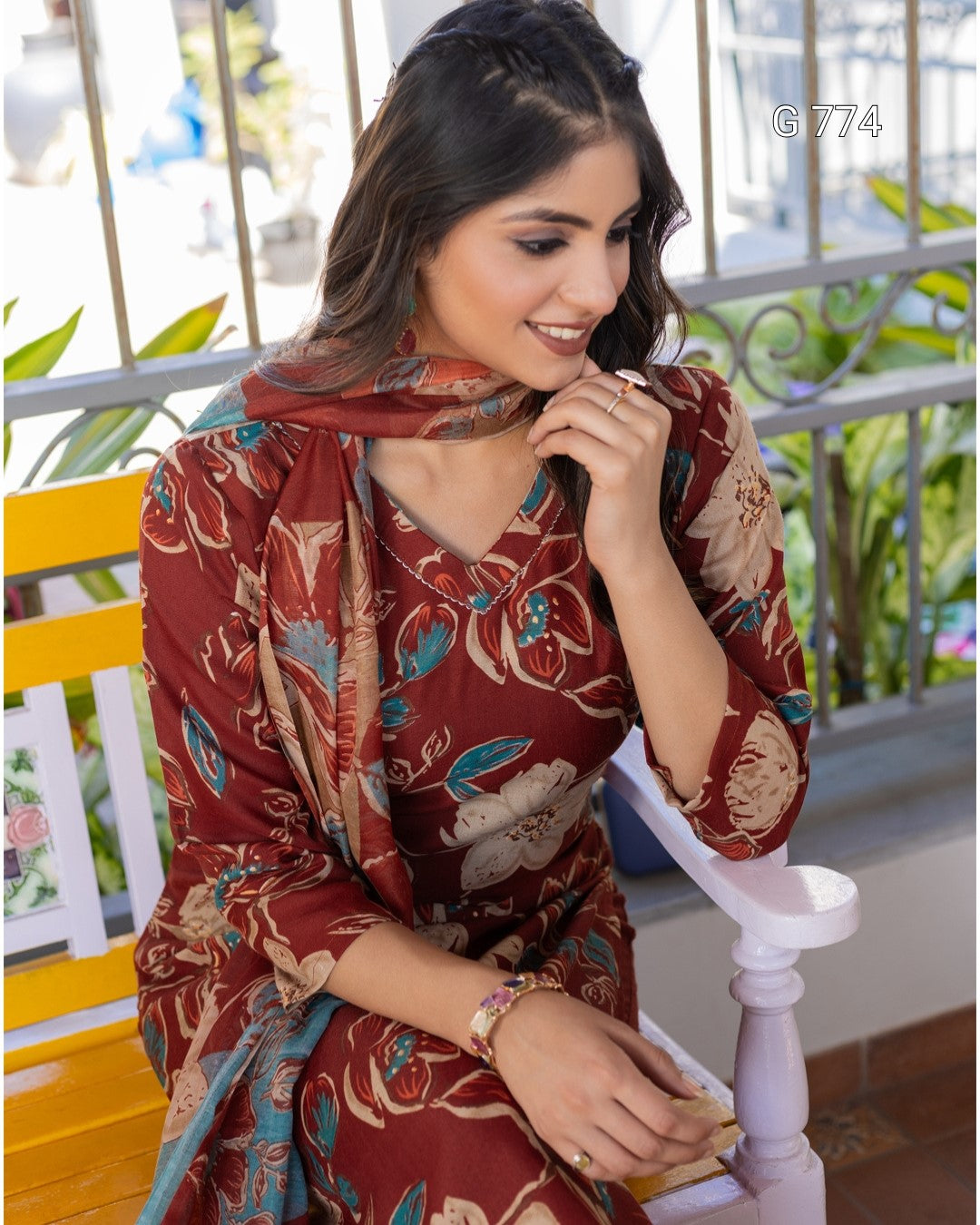 Woman wearing a patterned dress sitting on a chair with a blurred outdoor background