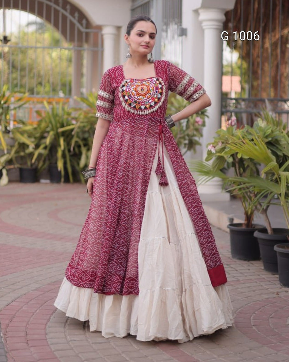 A woman modeling a traditional Indian salwar suit in a courtyard setting. The outfit features a dusty rose printed kurta with a heavily embroidered circular yoke, paired with a cream-colored flared skirt.