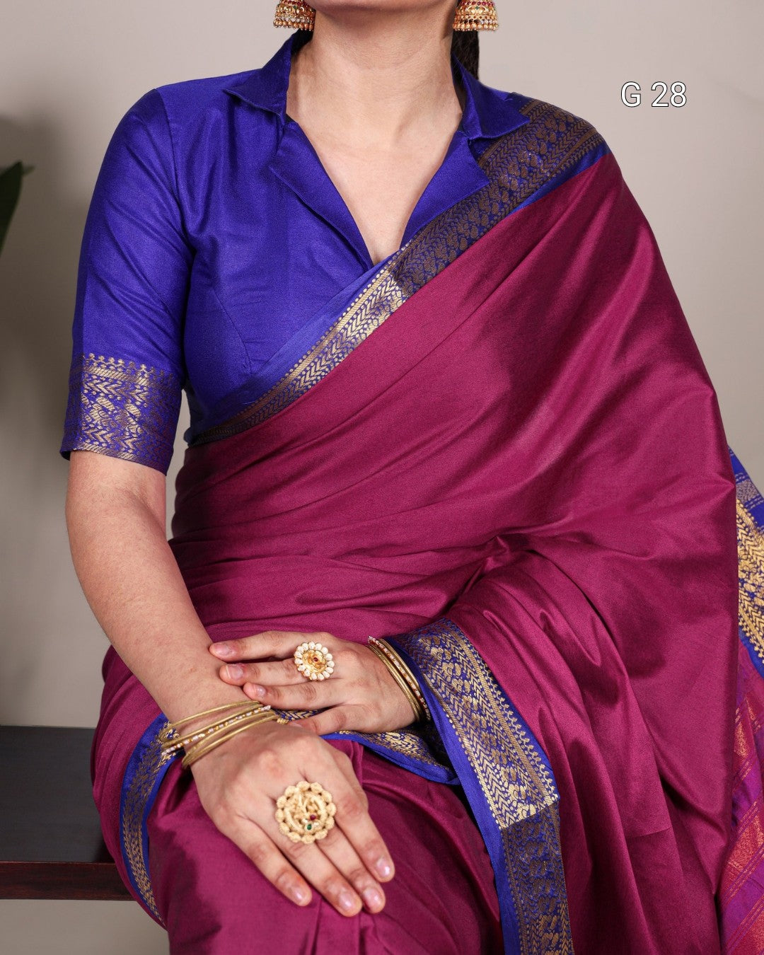 Person wearing a purple saree with gold border and jewelry