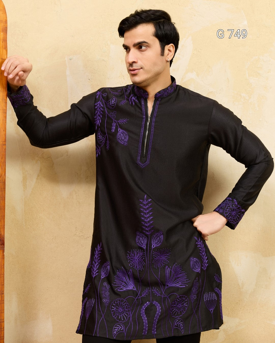 Man wearing a black kurta with purple embroidery against a beige background
