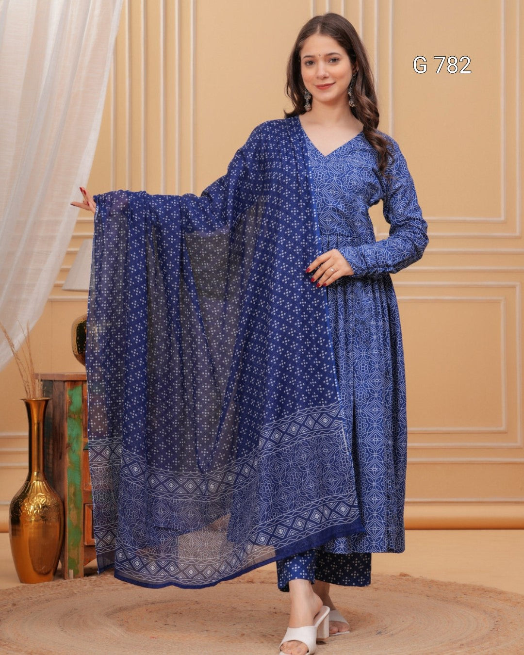 Woman wearing a blue patterned outfit with a matching dupatta in an indoor setting.