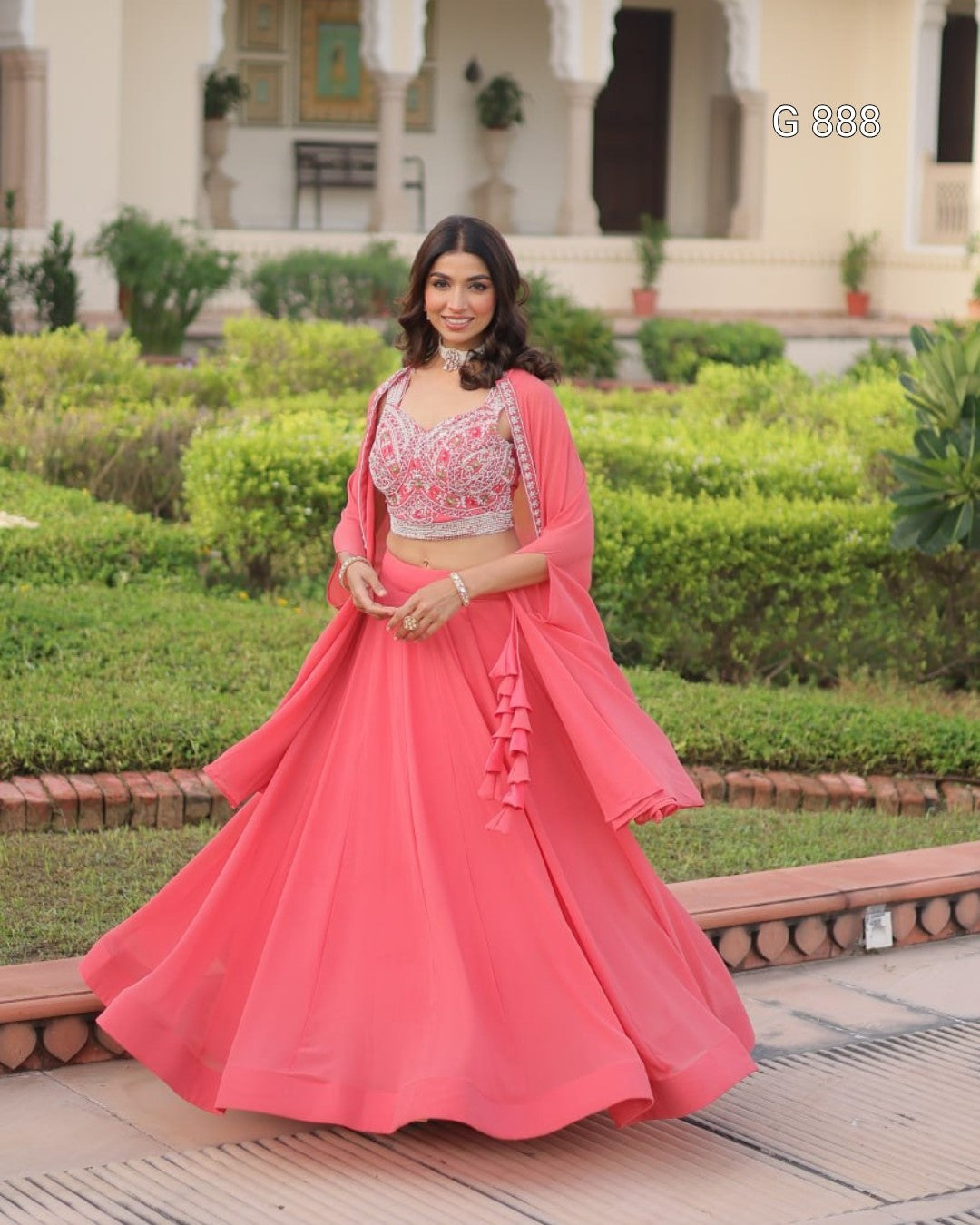 Woman in a pink traditional outfit standing in a garden setting