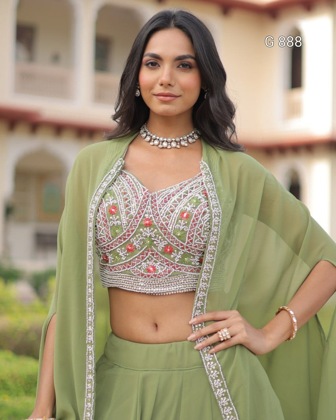 Woman wearing a green traditional outfit with intricate designs in an outdoor setting