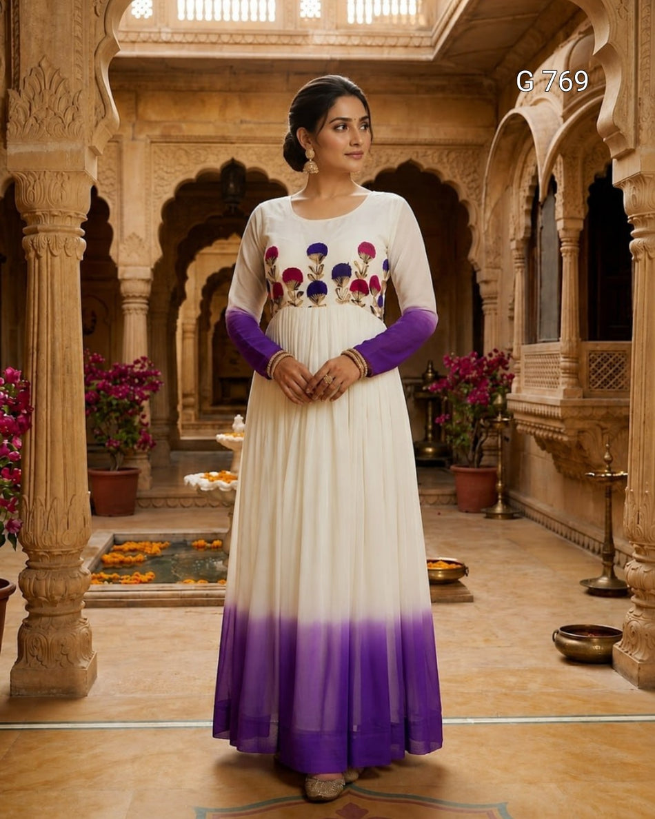 Woman in a white and purple traditional outfit standing in an ornate indoor setting.